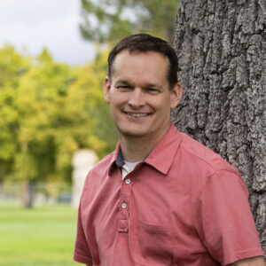 Dave Morrison standing by a tree and wearing a peach colored top