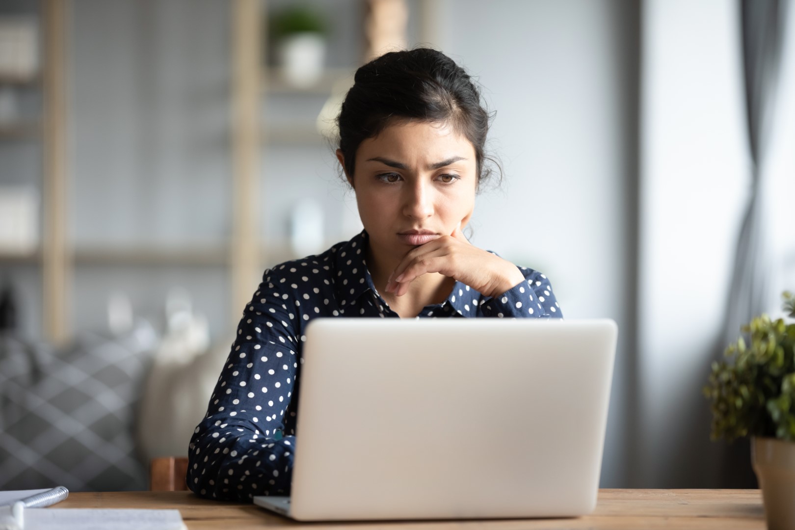Serious frowning indian woman read email on laptop feels concerned